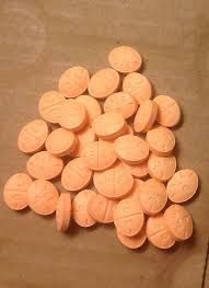 A pile of round orange tablets arranged on a flat surface.